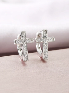 Macro shot of silver huggie earrings with cross pendants and pave-set zircons