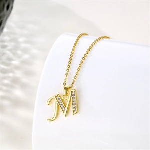 Close-up of golden letter M pendant with sparkling cubic zirconia on a 18K gold chain