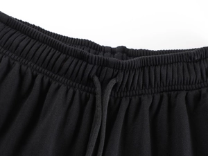 Detail of black sports trousers featuring an elastic waistband with adjustable drawstrings