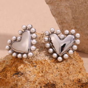 Macro shot of silver heart studs with white pearl border on a brown stone background