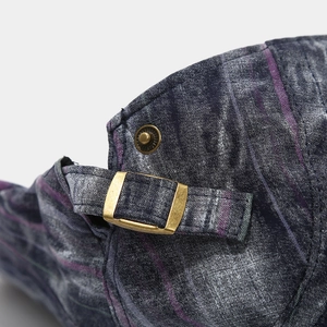 Detail of vintage canvas beret with adjustable copper buckle and purple striped fabric