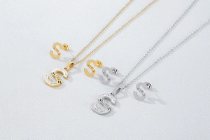 Close-up of S-letter necklace and stud earrings set with sparkling rhinestones in gold and silver