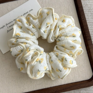 Detailed close-up of cream floral scrunchie with yellow flowers and lace embroidery