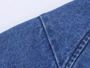 Detailansicht aus mittelblauem Denim-Stoff mit Köperbindung und feinen Nähten