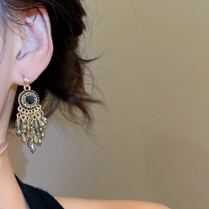 Close-up of vintage geometric earrings with black gems and grey crystal tassels