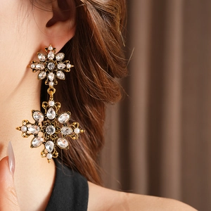 Détails de boucles d'oreilles vintage dorées avec strass et perles sur modèle