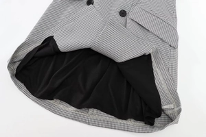 Detail of black and white houndstooth dress featuring stitching and buttons