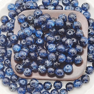 Detailed top view of deep blue 10mm glass beads with gold wire pattern in a wooden tray