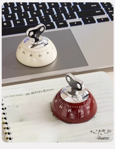 Detail of mechanical magnetic kitchen timers in beige and wine red on a study desk