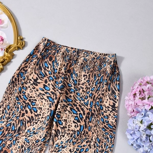 Detail of blue leopard print flared trousers with elastic high waist on gray background