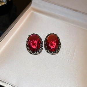 Detail view of oval ruby-red vintage studs with faceted cut in a jewelry box