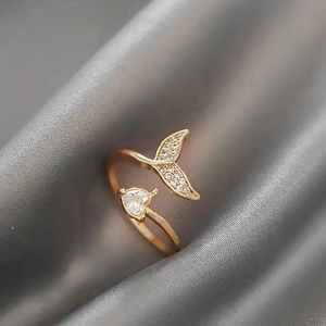 Macro view of gold mermaid tail ring with clear heart crystal on grey silk