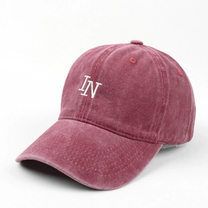 Detailed close-up of embroidered white IN letters on washed burgundy baseball cap