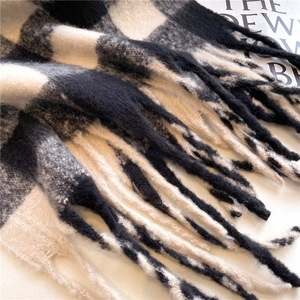Detail of classic black and white checkered scarf with thick tassels and soft cashmere texture