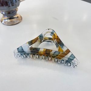 Detailed view of triangular tortoiseshell hair claw with marble texture and metal spring