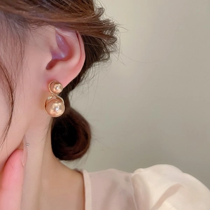 Gros plan d'élégantes boucles d'oreilles à double perle dorée portées sur un mannequin