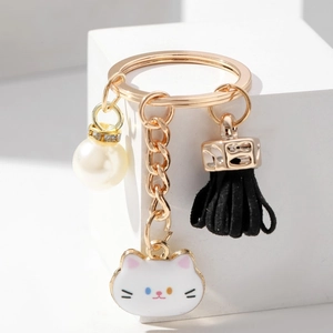 Detail of cute cat keychain with flower tassel and pearl bead on gold metal ring
