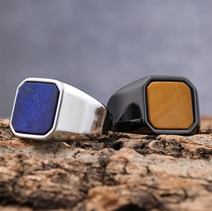 Polished stainless steel signet rings with lapis and tiger eye stones on rustic wood bark