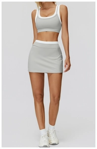 Detail of grey high-waisted tennis skirt and double-layered sports top on model