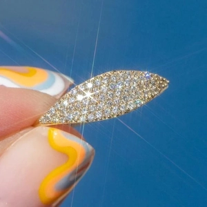 Marquise leaf gold ring with pavé crystals held against a clear blue sky