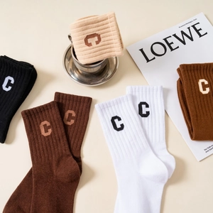 Macro detail of ribbed cotton socks with C embroidery and stylish magazine props