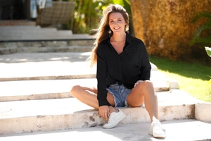 Close-up of black knit crinkle button-up beach cover-up shirt on a model outdoors