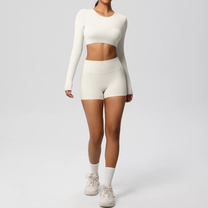 Detail of cream long sleeve crop top and high waist sports shorts on model in studio