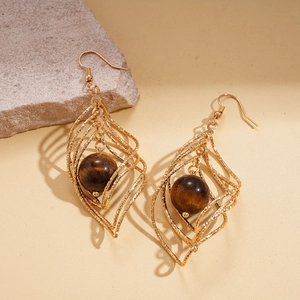 Detail of gold layered leaf earrings with brown tiger eye stone on a stone prop