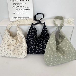 Détail de sacs à bandoulière en toile florale en crème, noir et vert exposés