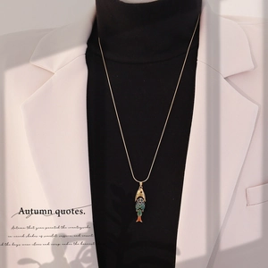 Detail of a vintage gold koi fish pendant with colorful enamel on a gold snake chain