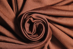 Macro shot of chocolate brown knitted fabric texture showing fine soft fiber weave