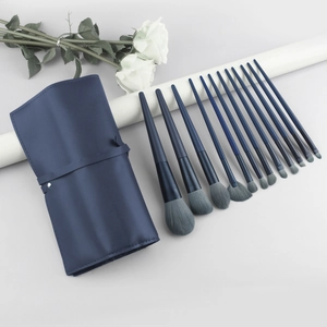 Detail of 13 professional makeup brushes with navy handles and a matching roll-up case