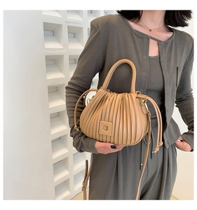 Detail of khaki pleated bucket bag showing vertical folds and soft PU leather texture