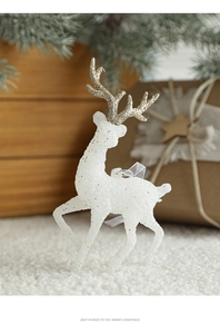 Detail of white Christmas reindeer figurine with gold glitter antlers on pine branches