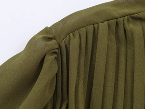 Detailed macro view of green chiffon dress pleated shoulder and metallic sleeve accents