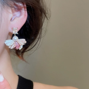 Macro shot of fan-shaped drop earrings featuring white pearls and zircon details