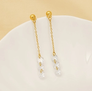 Detail view of long tassel earrings with three sparkling zircons on a white ceramic plate