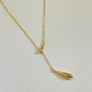 Detailed macro shot of a golden Y-shaped necklace with teardrop pendants on cross chain