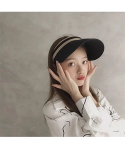 Dettaglio di un cappello da sole aperto nero e beige a righe indossato da una modella