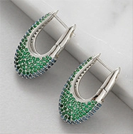 Macro shot of U-shaped silver earring hooks with inlaid green and blue tiny zircon stones