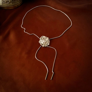 Silver metal rose flower bolo tie necklace with sleek snake chain on velvet background