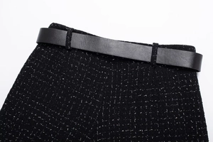 Détail de la texture en tweed et de la ceinture en cuir noir sur le short