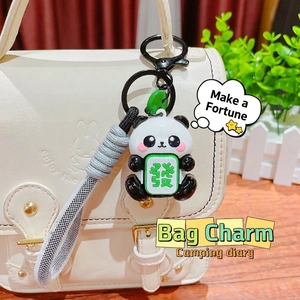 Cute panda keychain with mahjong tile charm and woven lanyard on a white handbag