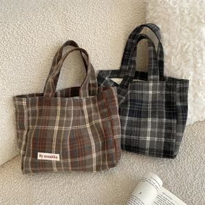 Macro detail of retro plaid canvas tote bags in brown and grey with a minimalist logo