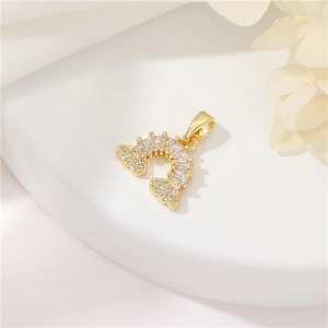 Macro view of 14k gold-plated rainbow charm with sparkling zircon stones and clouds
