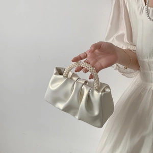 Detail of the pearlescent ruched cloud bag featuring a textured pearl bead handle