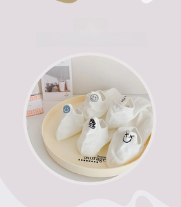 Detail of five pairs of white low-cut socks with cartoon embroidery on a tray