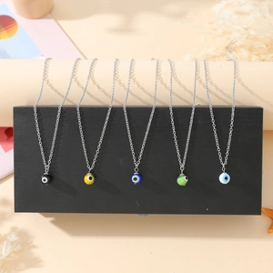 Detail showing five colors of evil eye pendant necklaces in a curated beach-style layout