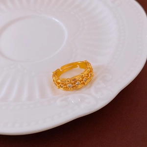 Gros plan d'une bague dorée texturée avec zircons posée dans une coupelle en céramique