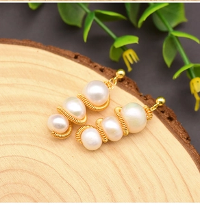 Macro shot of natural white pearl earrings with elegant gold wire wrapping detail